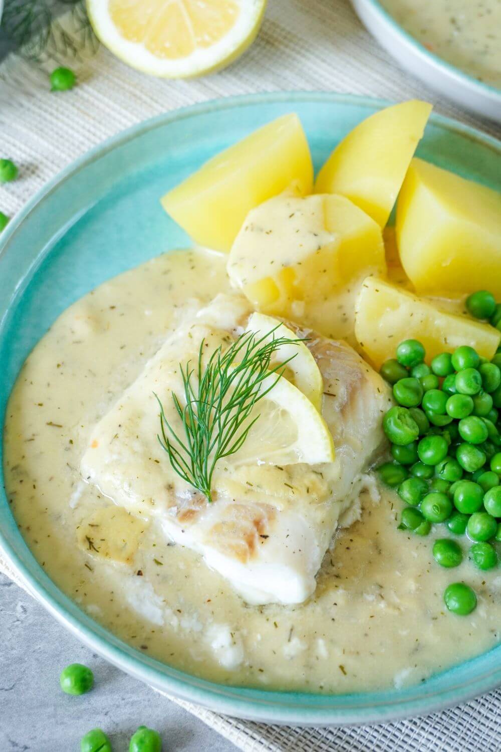 Teller mit Fisch in Senfsoße, Erbsen, Kartoffeln und Dill