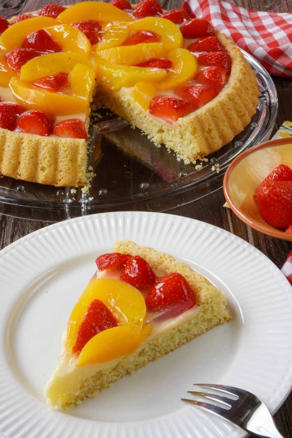Schneller Kuchen mit Pudding und Obst Stück Erdbeer-Pfirsich-Obstkuchen auf Teller